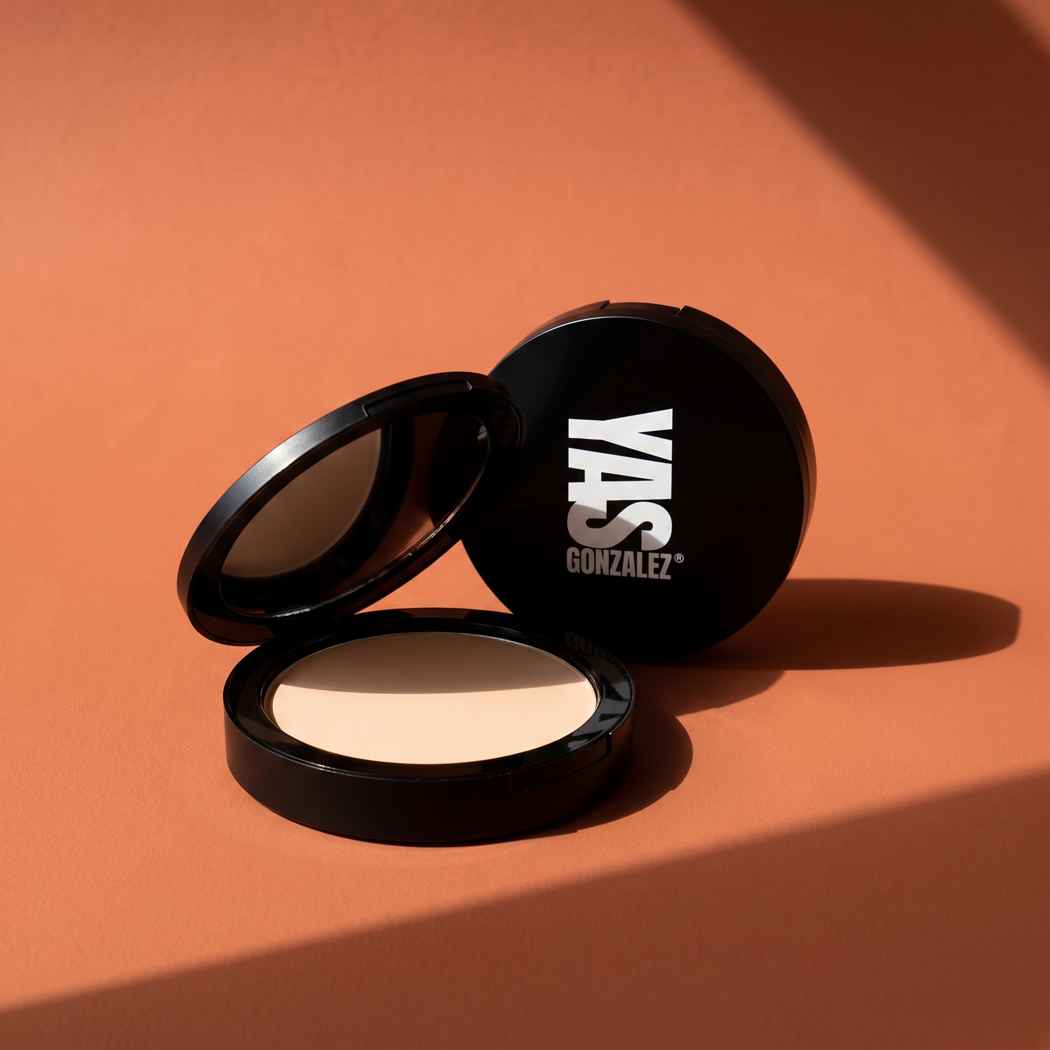 Dual Blend Powder Foundation de YG Beauty, compacto negro abierto sobre fondo terracota