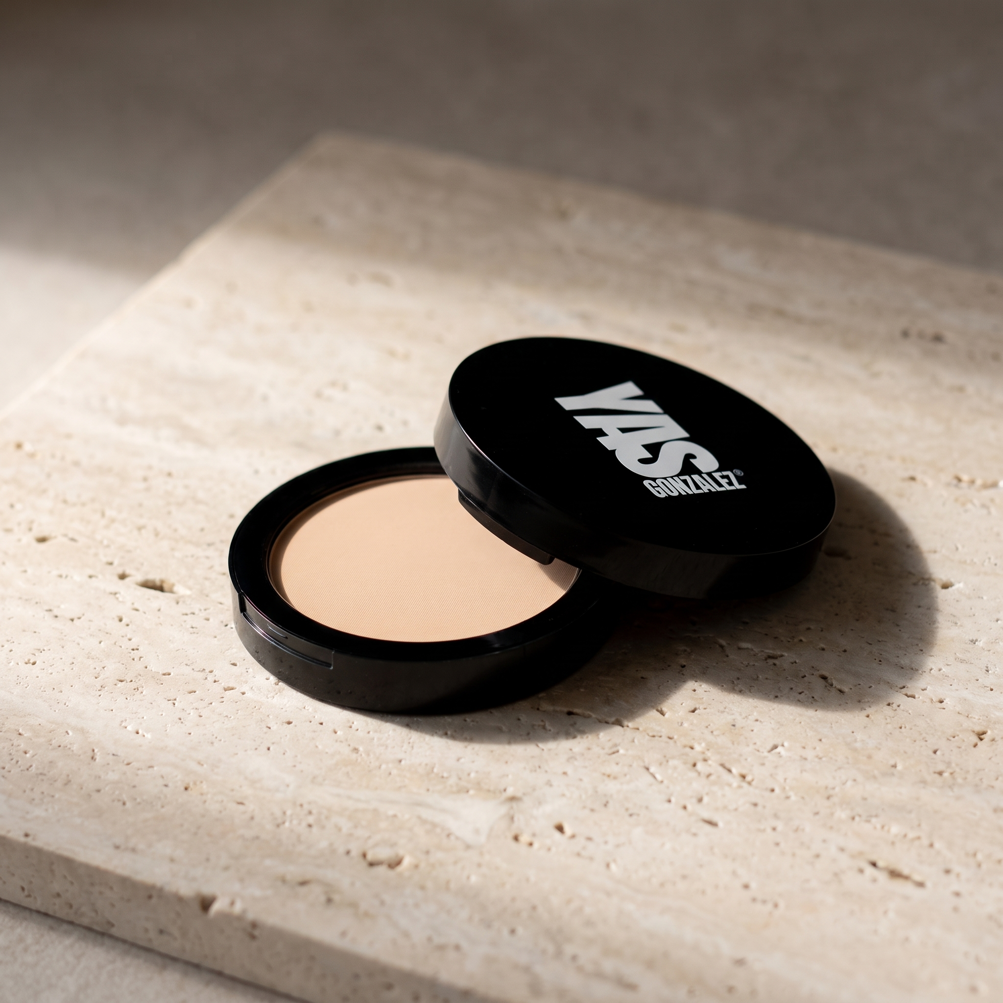 Dual Blend Powder Foundation de YG Beauty, compacto abierto sobre travertino