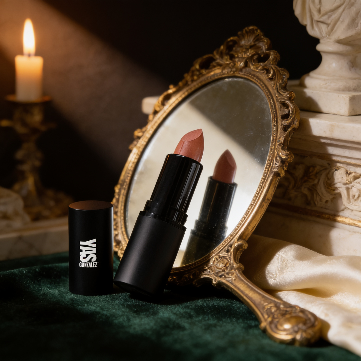 Lipstick beside a gilded hand mirror on green velvet